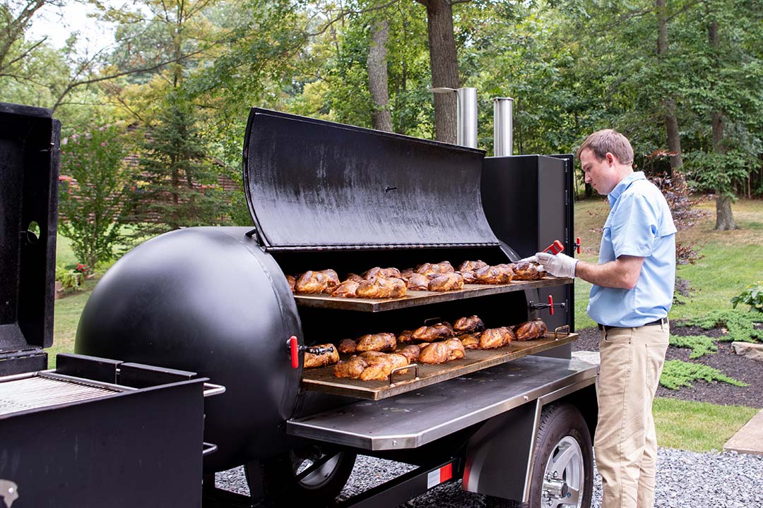https://www.meadowcreekbbq.com/wp-content/uploads/2020/09/Barbecue_Smoker_Trailer_Spatchcocked_Chickens_31_Checking_Temp_on_Top_Grate.jpg